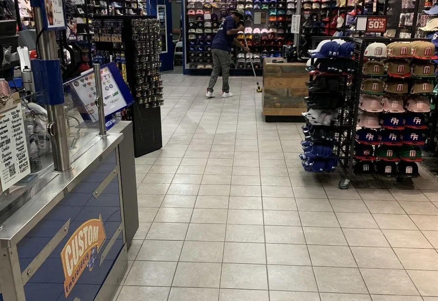 Cleaner working along a tiled walkway between retail merchandise displays